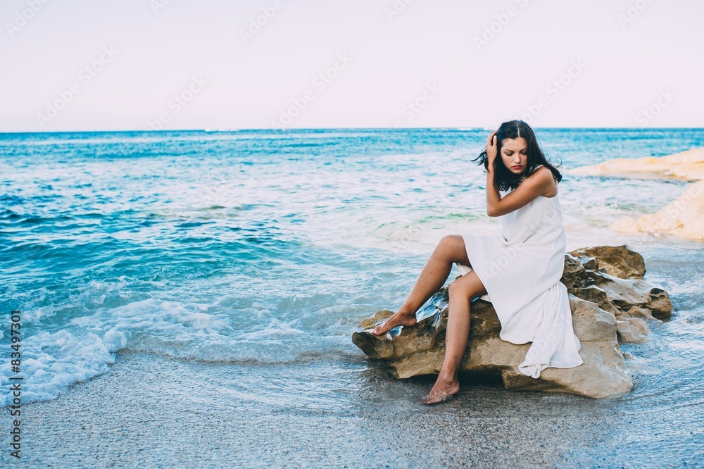 beautiful girl sitting on a rock on the beach sea Stock Photo | Adobe Stock