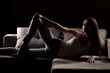 silhouette of young woman in jeans posing on the sofa
