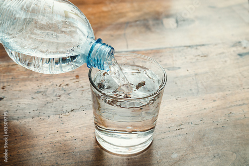 Zdjęcie XXL niebieska butelka wody wlewa się do przezroczystego szkła