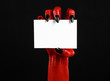 Red devil hand with black nails holding a blank white card