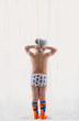 © RooM The Agency - Rear view of a boy in his underpants and socks looking through net curtains in front of a window