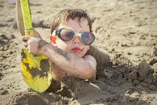 Boy (4-5 Years) Buried In Sand On Beach
