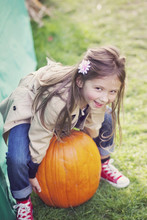 Girl (4-5) Trying To Lift Big Pumpkin