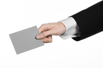 Man in black suit holding a gray blank card in hand isolated