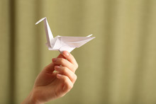 Female Hand With Paper Crane On Blurred Background