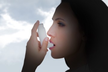 Poster - Composite image of asthmatic brunette using her inhaler 