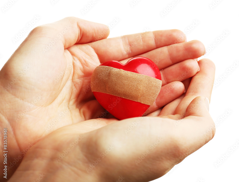 Female hands holding heart with plaster isolated on white