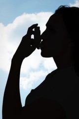 Poster - Composite image of asthmatic brunette using her inhaler 