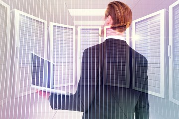 Poster - Composite image of businessman looking up holding laptop