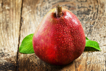 fresh red pear with drops of water on wooden table, selective fo