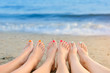 Female legs with color pedicure on the background of the sea