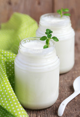 Homemade yogurt in two small glass jars on a wooden table 