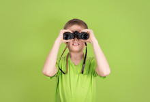 Boy With Binoculars Isolated On Green Background Copyspace. 