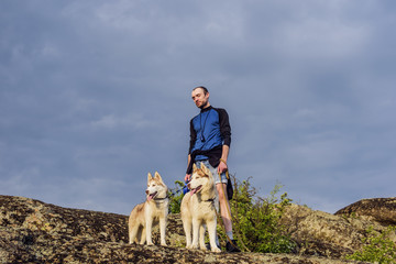 Wall Mural - young caucasian male hiking with huskies in mountains