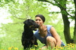 Junge Frau mit schwarzem Hund auf Wiese Löwenzahn