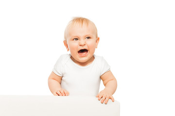 Angry small baby with open mouth in white bodysuit