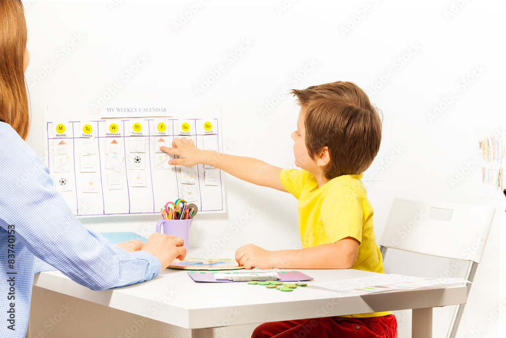 Boy points at activities on calendar learning days