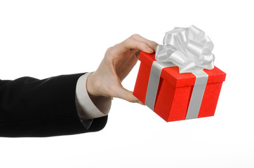 man in a black suit holding gift wrapped in red box