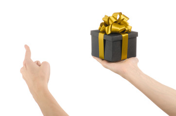 Wall Mural - hand holding a gift wrapped in a black box with gold ribbon