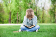 © Masson - sad boy with book on green grass