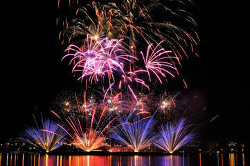 Firework over city at night with reflection in water