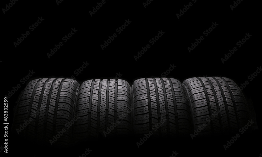 four automobile rubber tires isolated on black background - obrazy, fototapety, plakaty 