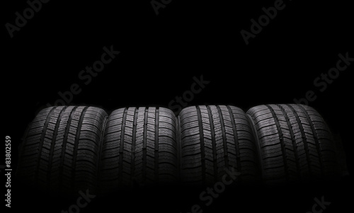 Fotomural four automobile rubber tires isolated on black background