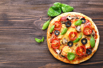 Wall Mural - Tasty pizza with vegetables and basil on wooden background