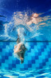 Swimming girl jumps deep down underwater in the blue pool