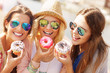 © Kalim - Group of friends eating donuts in the city