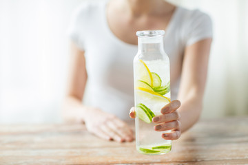 Wall Mural - close up of woman with fruit water in glass bottle