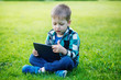 © Volha Zaitsava - little boy with tablet sit on the grass
