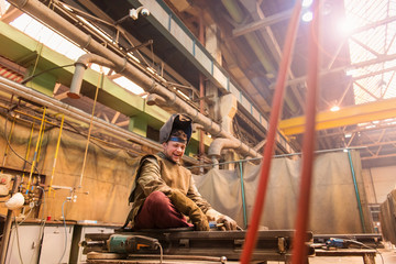 Wall Mural - Young man in protective workwear welding in a factory