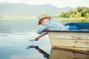 Wall Mural - Little boy launch paper ship lying in old boat