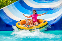 Child With Mother On Water Slide At Aquapark.