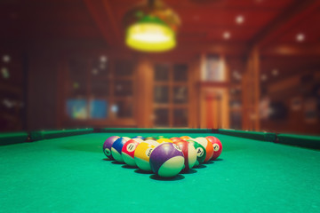 Billiard balls on green pool table in bar or pub