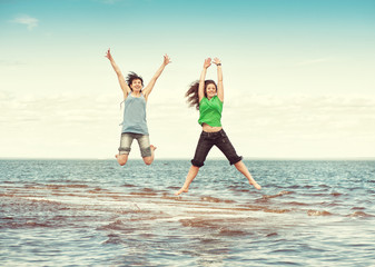 Two happy women jumping in the water of sea