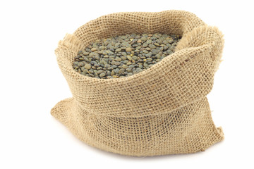 French green lentils (lentilles du Puy) in a burlap bag on a white background