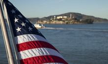 An American Flag With Alcatraz Island In The Distance