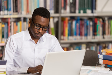 Young Student Using His Laptop In A Library