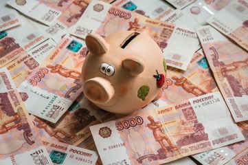 Piggy bank in a pile of russian five thousand banknotes