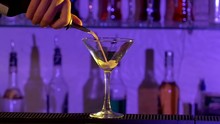 Barman Pouring A Liqueur Cocktail Into Glass In Bar, Slow Motion