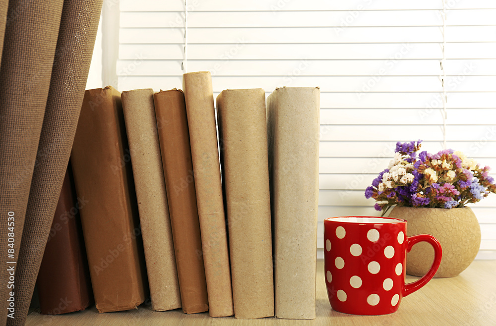Books, cup and plant on wooden windowsill, closeup