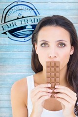Poster - Composite image of pretty brunette eating bar of chocolate