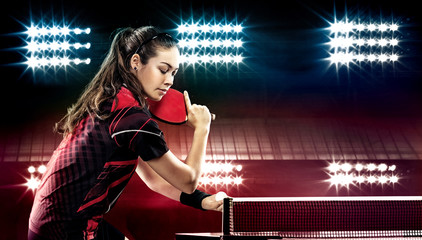 Young pretty sporty girl playing table tennis on black