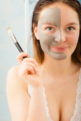 Woman applying mud facial mask