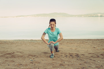 Poster - Woman stretching her legs before running on beach