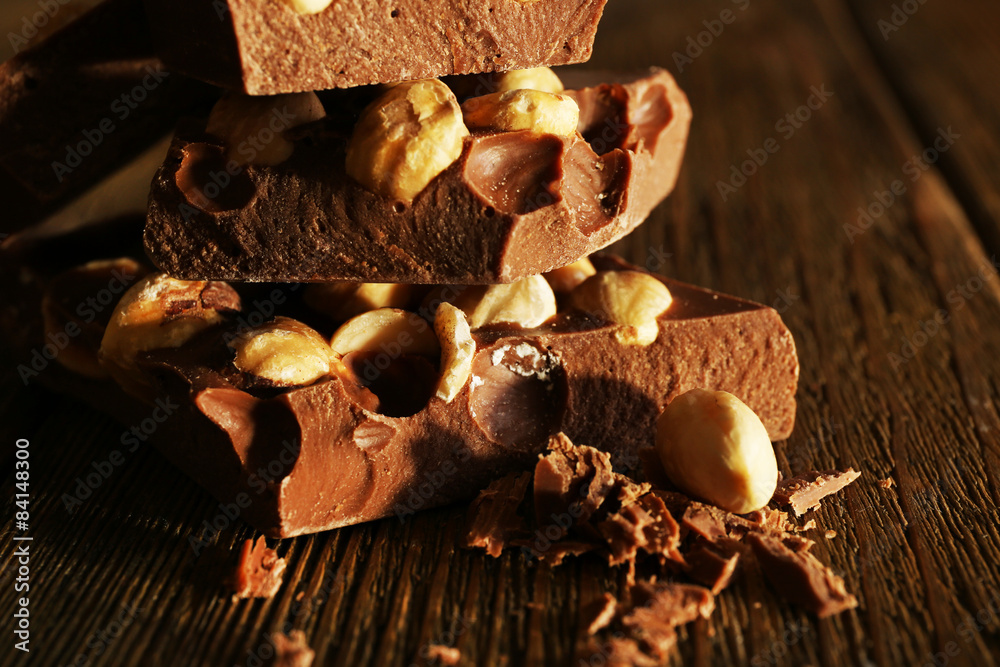 Stack of chocolate with nuts on wooden table, closeup