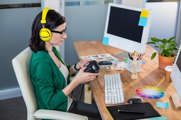 Wall Mural - Brunette holding digital camera and listening music