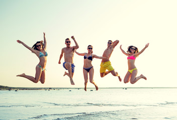 Wall Mural - smiling friends in sunglasses on summer beach